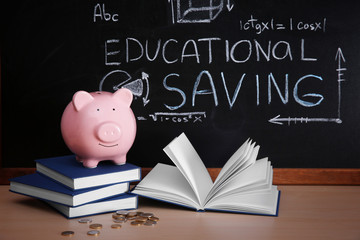 Piggy bank with books and coins on blackboard background. Educational savings concept