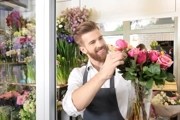 Photo sur Aluminium Fleuriste Young handsome florist with beautiful bouquet at flower shop