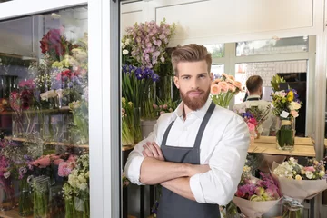 Photo sur Plexiglas Fleuriste Portrait of young handsome florist with crossed arms in flower shop
