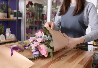 Crédence de cuisine en verre imprimé Fleuriste Female florist packing beautiful bouquet in wrapping paper at flower shop