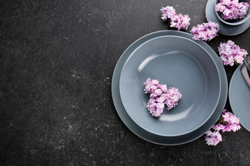 Obraz na płótnie Canvas Beautiful festive table setting with lilac flower decor on dark background