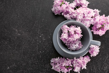 Obraz na płótnie Canvas Cup with saucer and lilac floral decor on dark background