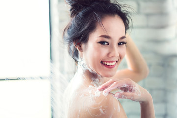 Asian women are taking a shower in the bathroom she is rubbing soap,she is happy and relaxed.