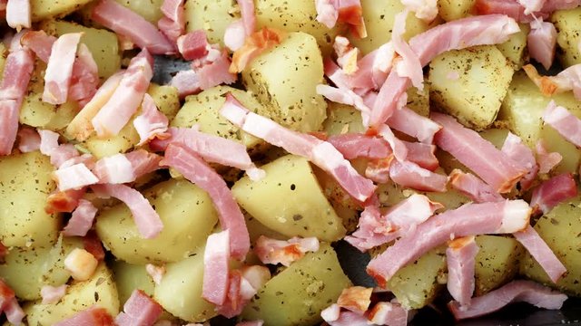 Peeled potatoes with spices, becon meat and onion slices ready to be roasted close up. Food background. Dolly shot 4K ProRes HQ codec