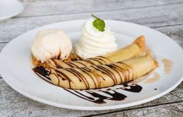 Banana crepes with vanilla ice cream and home made whip creme, glaze with chocolate and honey , selective focus