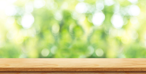 Empty brown wood table top with green blur nature background and sun light,Mock up for display or montage of product,panoramic view,banner size for advertise on online media