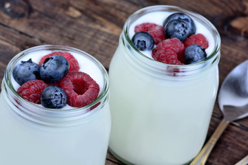 Berries with yogurt in a jars on table