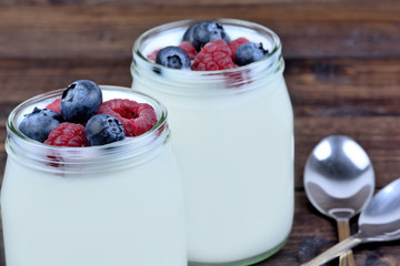 Jars with yogurt ans assorted berries on table