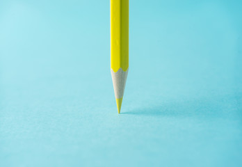 Business concept - one yellow color pencil stand on blue paper background. It's symbol of key point...