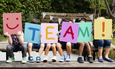 Children are sitting on the wooden table holding a word team