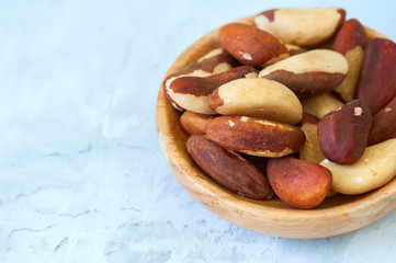 Close up of brasil nuts in a wooden plate on white background