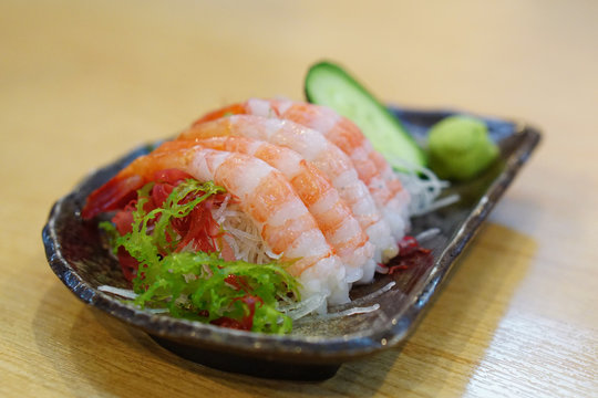 Fresh Amaebi (Sweet Shrimp) Sashimi Set served with wasabi, zucchini seaweed and grated radish on plate.