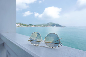 Sunglasses accessories for travel on the beach. Blue sea beach, sunglasses placed on the sand beach.