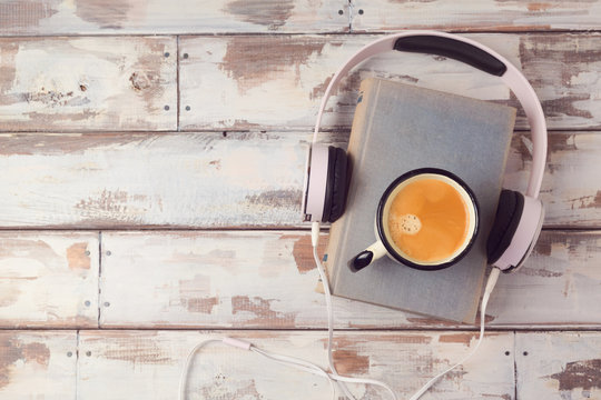 Audio book concept with old book, headphones and coffee cup. View from above. Flat lay