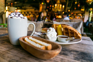 A plate of waffle with banana, whipping cream, blueberry and syrup, delicious, yummy