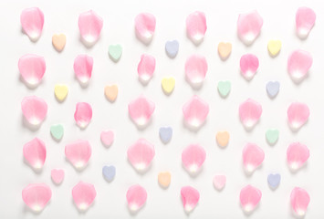 Candy hearts and rose petals on a white background