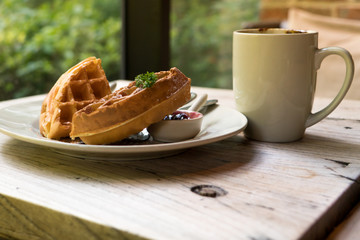 2 pieces of waffle with a white cup of coffee on the wooden table