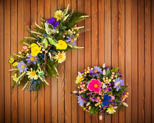 Fototapeta na wymiar Colorful composition made of artificial flowers, fruits, butterflies and ears of wheat in stylish vase on white wooden background.