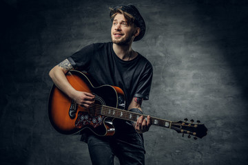 Obraz premium Fashionable hipster blues and jazz acoustic guitar player with tattoos on his arms.