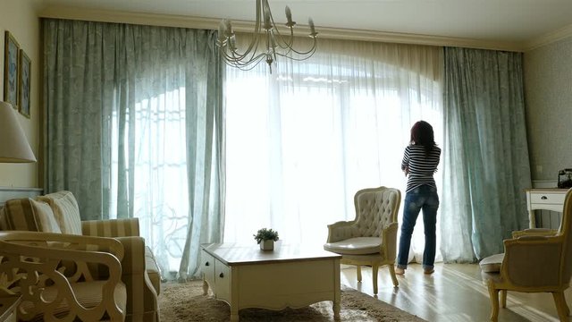 Upset woman going forth and back along the window of a cozy apartment