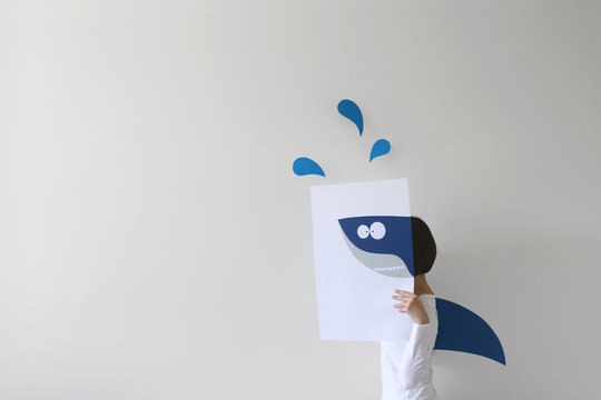 Woman holding paper with a shark drawing and wearing a shark fin