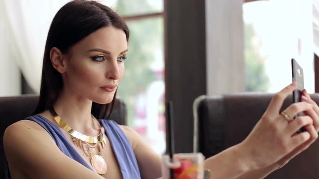 Girl in evening dress taking a selfie in the restaurant.