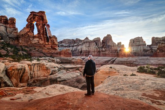 Man looking at Druid Arch at sunset, Canyonlands National Park, Utah, America, USA