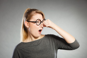 Girl pinches her nose because of stench stink.