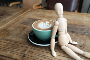 Hot mocha coffee or capuchino in the green cup lean by wood man on the wooden table