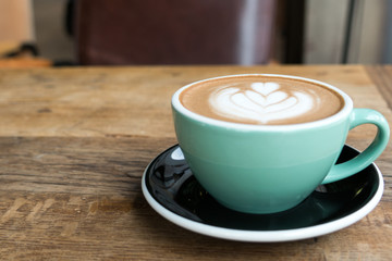 Hot mocha coffee or capuchino in the green cup with heart pattern on the wooden table