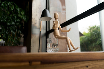 wood man is sitting on a glass of water