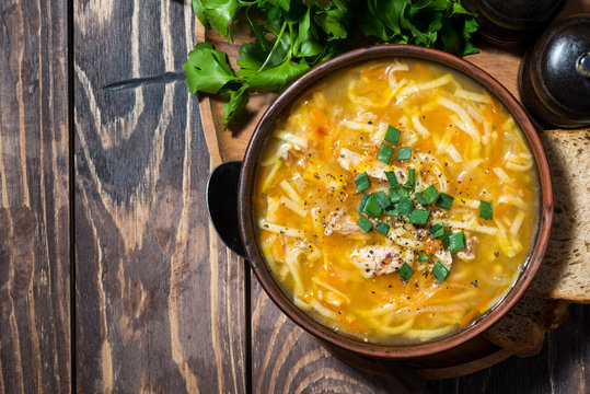 chicken soup with egg noodles on wooden background, top view