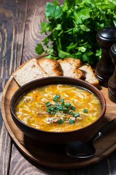 chicken soup with egg noodles on wooden background, vertical