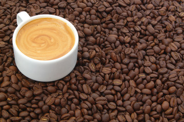 Cup of espresso coffee on roasted coffee beans background