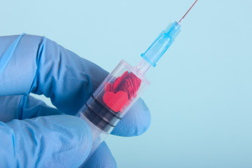 Injection of love. A hand in the glove holds a Syringe with red hearts