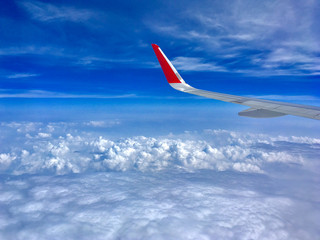 airplane wing flying above the clouds with blue sky.