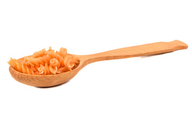 Carrot pasta fusilli in a wooden spoon on a white background