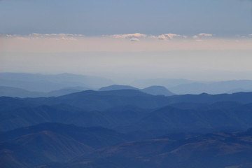 Fototapeta premium Hazy blue ridges of Slovak Ore Mountains and Slovak Paradise National Park under white clouds from Lomnicky peak, High Tatras, Slovakia, Europe