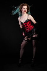 Beautiful woman in fetish red leather corset on black background in studio photo. BDSM and...
