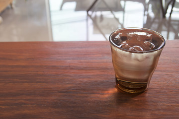 A glass of water with ice on wooden table.