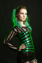 Sexy Woman in cosplay corset posing in studio with a green light from behind. Studio photo. Fashion and cosplay