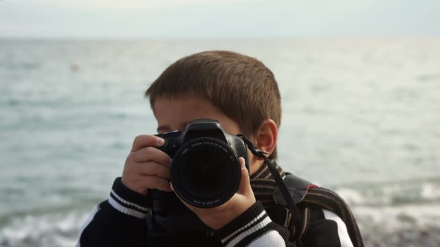 boy with photo camera makes a shoot on the bach