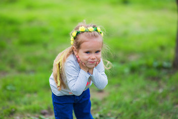 Portrait of a cute little girl in a wreath of flowers in a summer park