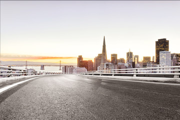 empty road with modern city at sunrise