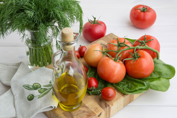 Olive oil, parsley, spinach and branch of tomatoes on a white background