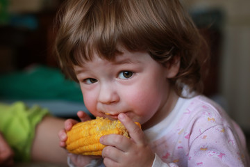 little boy eats greedily biting corn