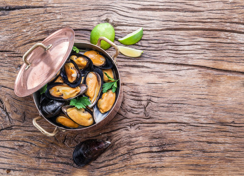 Mussels in copper pan on the wooden table.