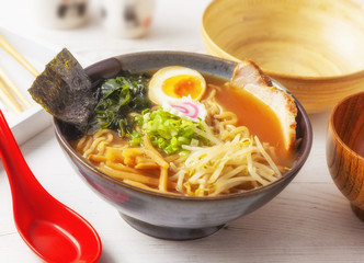 Miso Ramen Asian noodles with meat and egg in bowl on white wooden background.