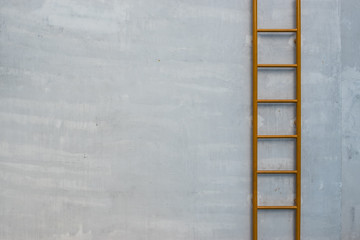 Yellow fixed ladder on the raw concrete wall background