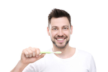 Portrait of handsome young man brushing teeth on white background